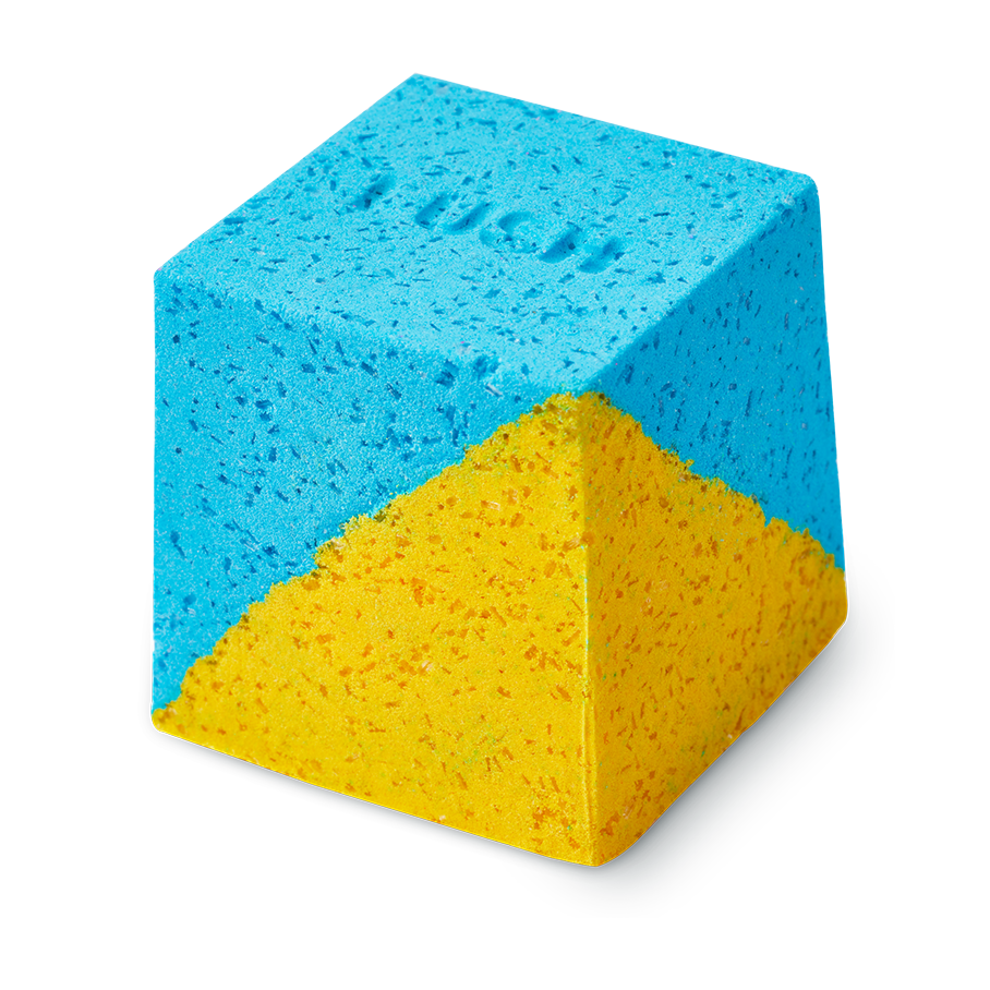 Salt Water Soother. A cube-shaped bath bomb with a split-colour design of bright blue and yellow. The top face features a debossed "LUSH" logo. The texture is coarse and granular with visible Epsom salt throughout.